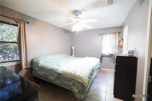 bedroom featuring ceiling fan, a textured ceiling, and light tile patterned floors