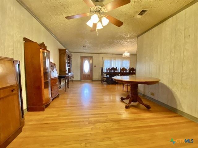 dining area with light wood finished floors, visible vents, a textured ceiling, and ceiling fan with notable chandelier