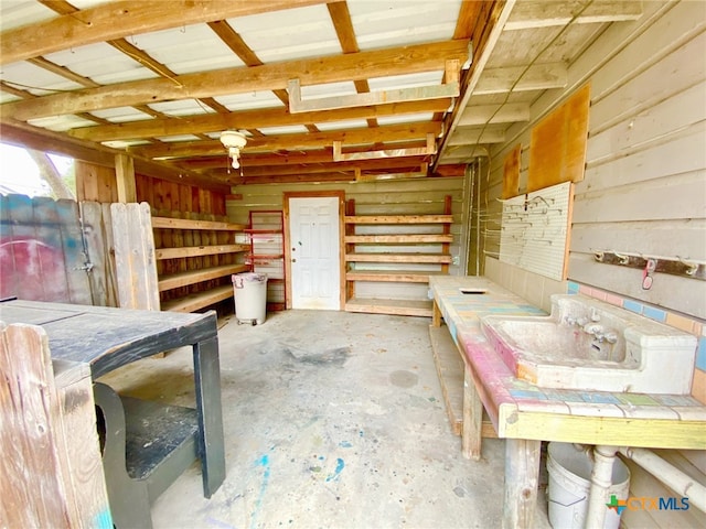 misc room with wooden walls and unfinished concrete floors