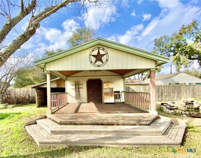 wooden deck featuring a carport, an outdoor structure, and fence