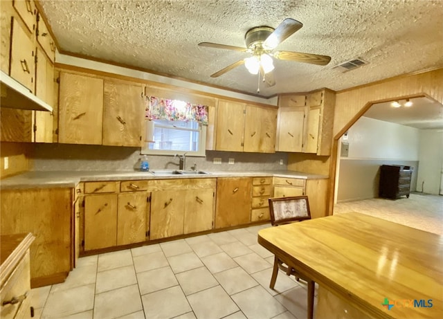 kitchen with a textured ceiling, ceiling fan, a sink, visible vents, and light countertops