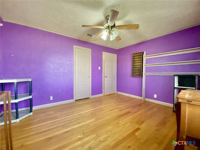 unfurnished bedroom with baseboards, visible vents, ceiling fan, wood finished floors, and a textured ceiling