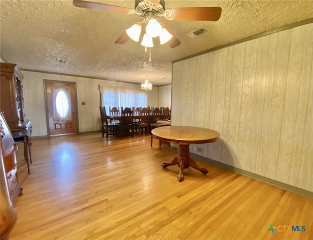 dining room featuring ceiling fan with notable chandelier, visible vents, a textured ceiling, and wood finished floors