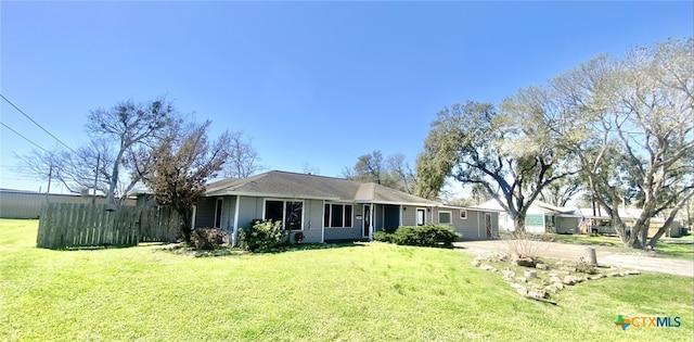 ranch-style house featuring concrete driveway, a front yard, and fence