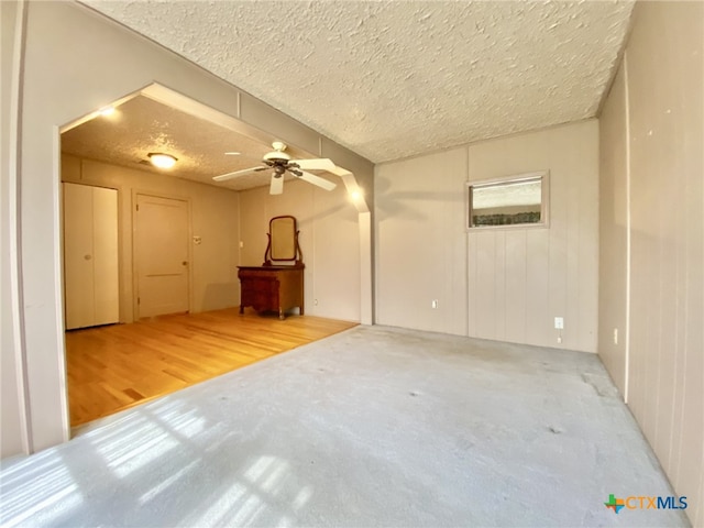 empty room featuring ceiling fan, a textured ceiling, and wood finished floors