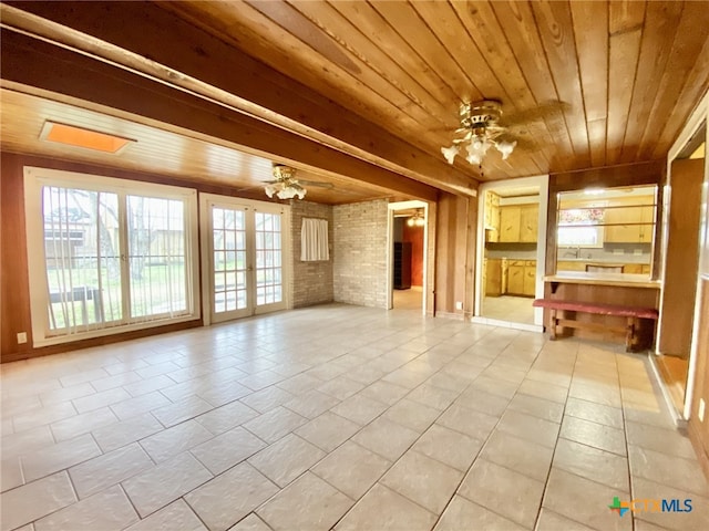 unfurnished living room featuring a ceiling fan, wooden ceiling, and tile patterned floors