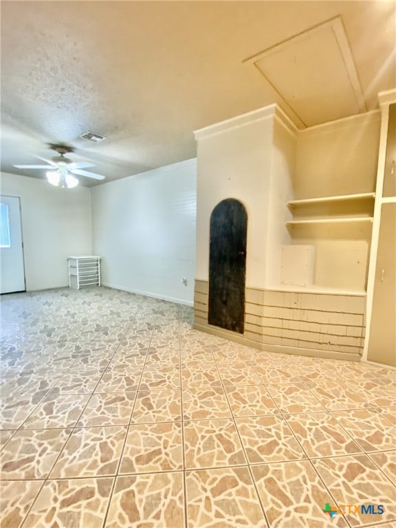 unfurnished living room with attic access, visible vents, ceiling fan, and a textured ceiling