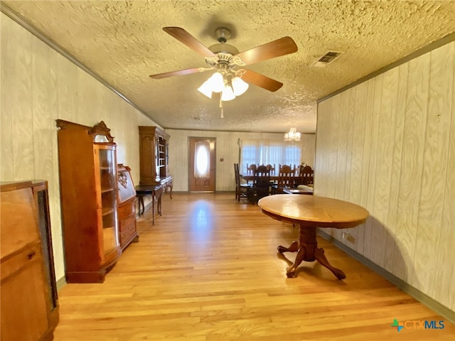 interior space featuring a textured ceiling, ceiling fan with notable chandelier, light wood-type flooring, and visible vents