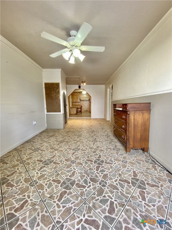 additional living space with a ceiling fan, arched walkways, and stone finish flooring