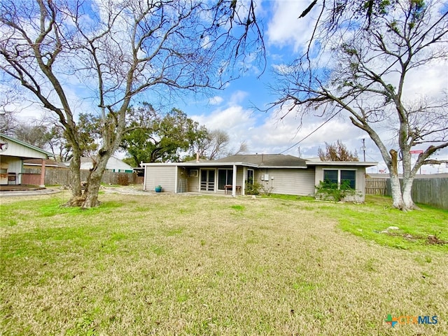 back of property with a lawn and fence