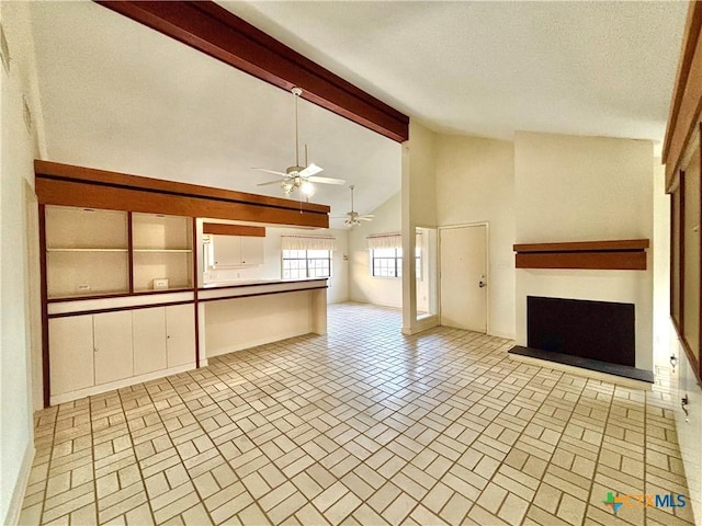 unfurnished living room with a fireplace with raised hearth, ceiling fan, beamed ceiling, high vaulted ceiling, and brick patterned floor