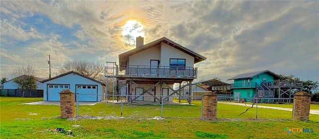 back of property with a lawn, a detached garage, stairway, an outbuilding, and fence