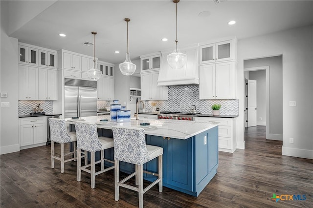 kitchen featuring hanging light fixtures, white cabinetry, a large island, and stainless steel built in fridge