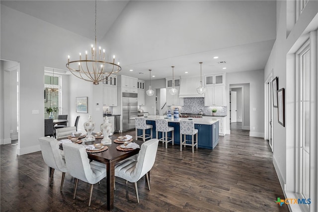 dining room with dark hardwood / wood-style floors, a notable chandelier, and high vaulted ceiling