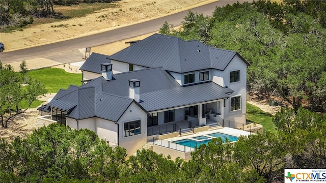 rear view of house featuring a patio and an in ground hot tub