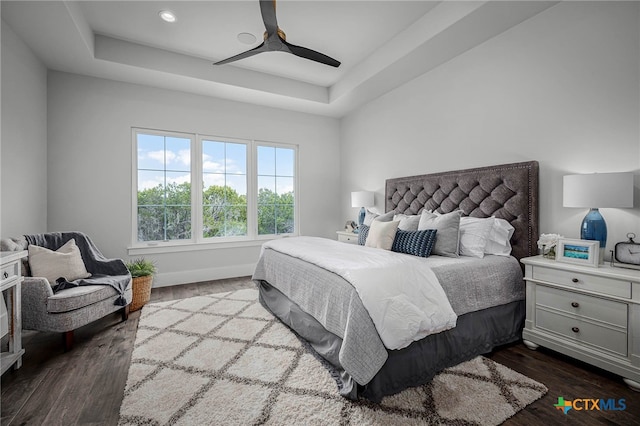 bedroom with a raised ceiling, hardwood / wood-style floors, and ceiling fan