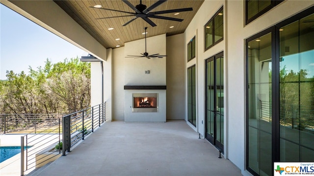 balcony with a patio, a large fireplace, and ceiling fan