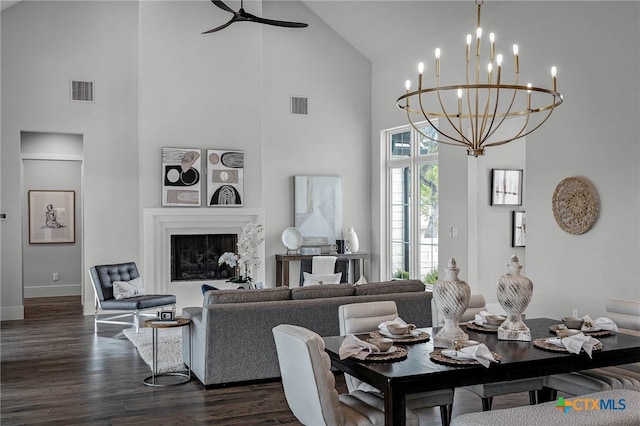 dining room with a premium fireplace, high vaulted ceiling, ceiling fan with notable chandelier, and dark hardwood / wood-style flooring