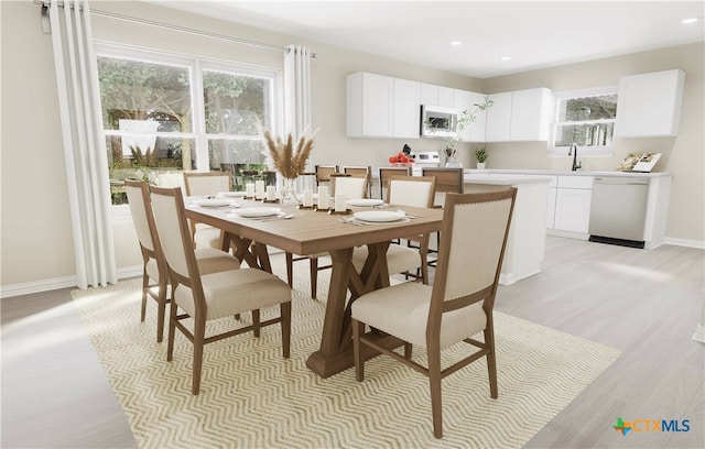 dining area featuring light wood-type flooring, a wealth of natural light, and sink