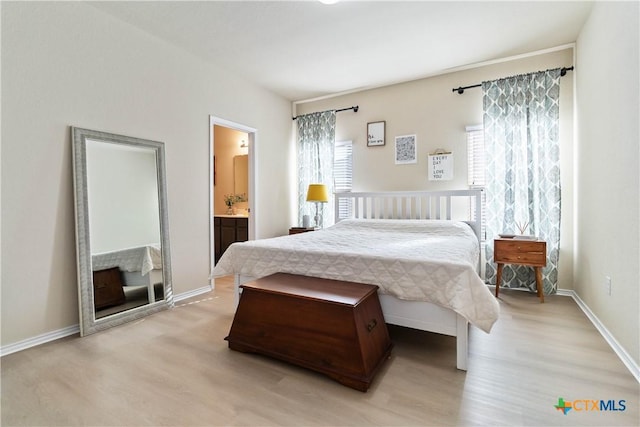 bedroom with ensuite bath and light hardwood / wood-style floors