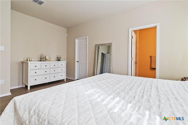 bedroom with connected bathroom and dark wood-type flooring