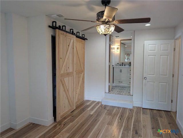 127 Forest Mist, Canyon Lake, TX 78133 - unfurnished dining area featuring visible vents, a barn door, baseboards, wood finished floors, and a ceiling fan