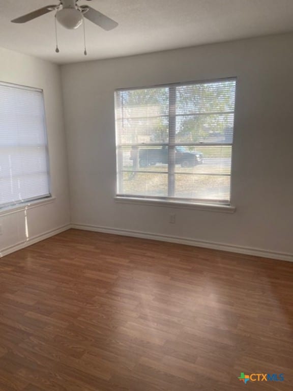 empty room with dark hardwood / wood-style floors and ceiling fan