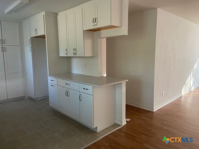 kitchen featuring kitchen peninsula, dark hardwood / wood-style flooring, and white cabinetry