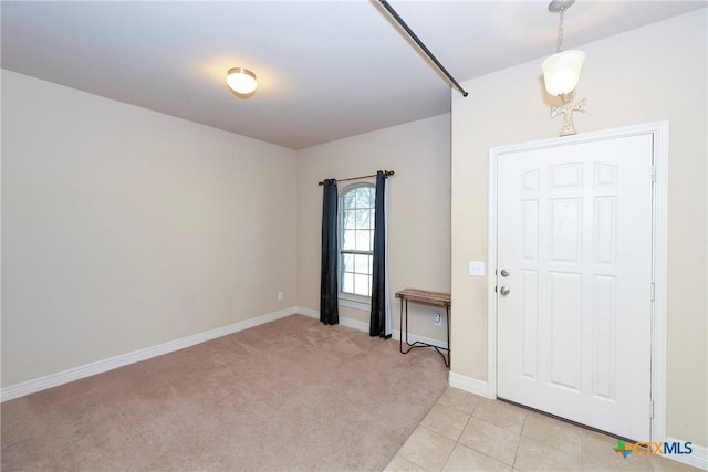foyer featuring baseboards and light colored carpet