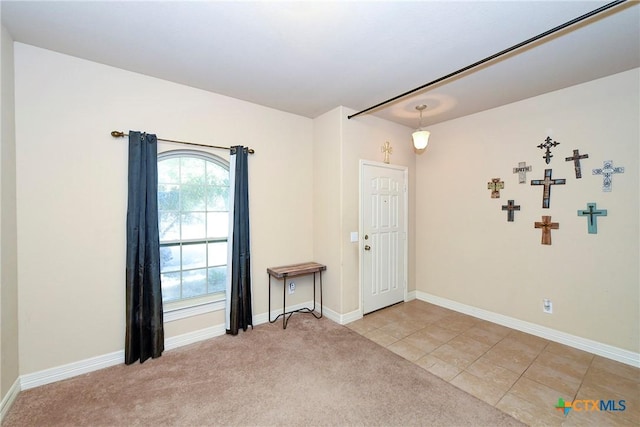 unfurnished room featuring light colored carpet, baseboards, and light tile patterned floors