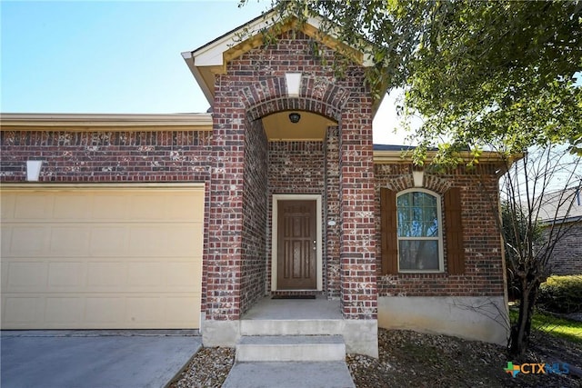 entrance to property with brick siding, driveway, and a garage