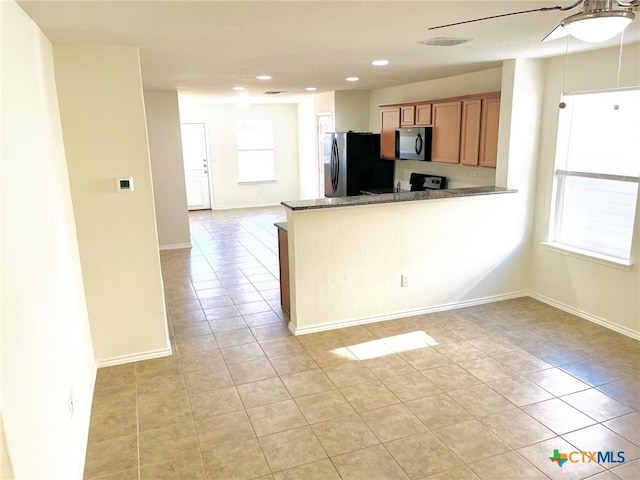 kitchen with kitchen peninsula, stainless steel fridge, and light tile patterned flooring