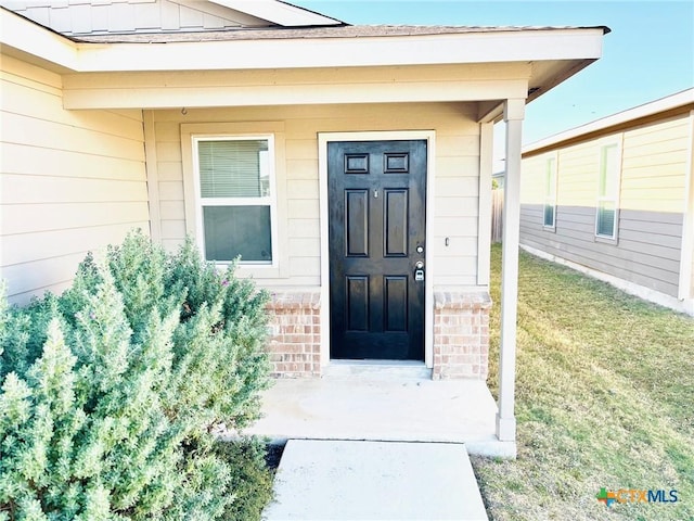 view of exterior entry featuring a lawn