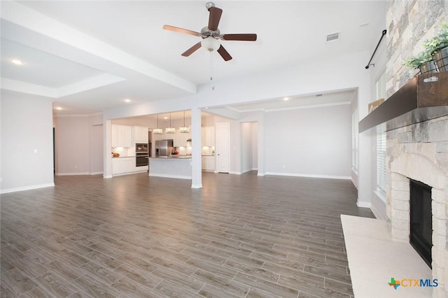unfurnished living room featuring visible vents, wood finished floors, a fireplace, baseboards, and ceiling fan