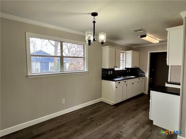 kitchen featuring white cabinets, a notable chandelier, pendant lighting, and ornamental molding