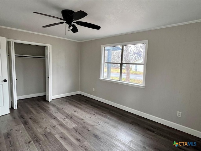 unfurnished bedroom with ceiling fan, a closet, dark hardwood / wood-style floors, and ornamental molding