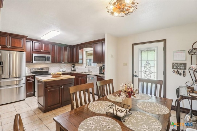 103 Misty Bnd, Floresville, TX 78114 - kitchen featuring light tile patterned floors, a sink, backsplash, appliances with stainless steel finishes, and a kitchen island
