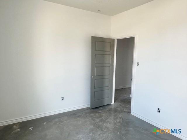 unfurnished room featuring concrete floors and baseboards