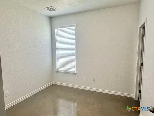 empty room with baseboards, visible vents, finished concrete floors, and a textured ceiling