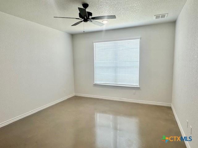 empty room with visible vents, a ceiling fan, baseboards, concrete floors, and a textured ceiling