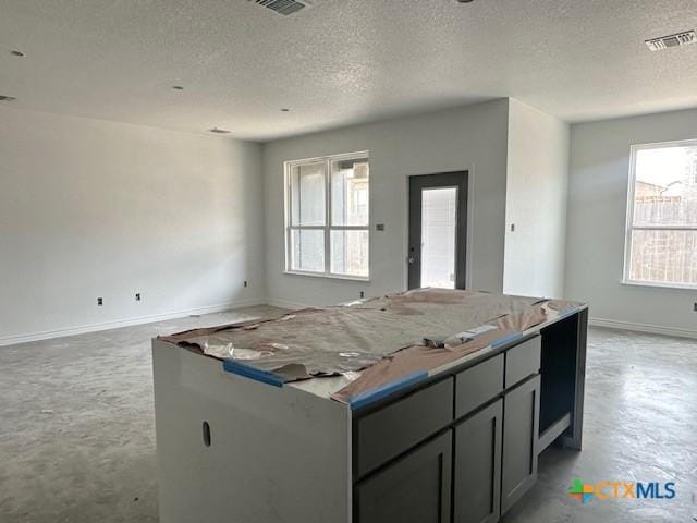 kitchen featuring visible vents, open floor plan, a kitchen island, concrete floors, and baseboards