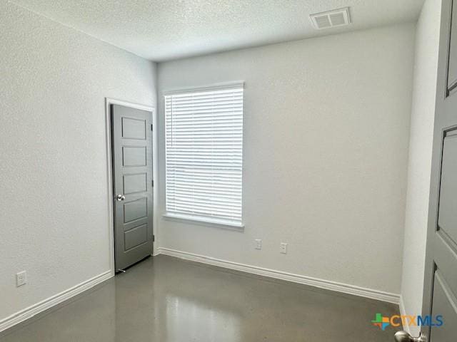 empty room featuring baseboards, visible vents, a textured ceiling, and concrete floors