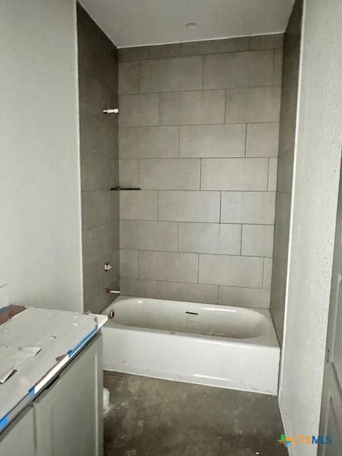 bathroom with tub / shower combination, concrete floors, and vanity