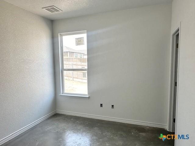 unfurnished room with a textured ceiling, concrete floors, visible vents, and baseboards