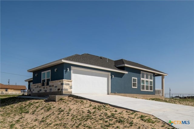 view of front of property featuring a shingled roof, stucco siding, driveway, stone siding, and an attached garage