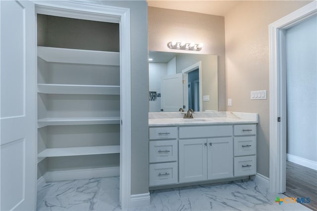 bathroom with marble finish floor, vanity, and baseboards