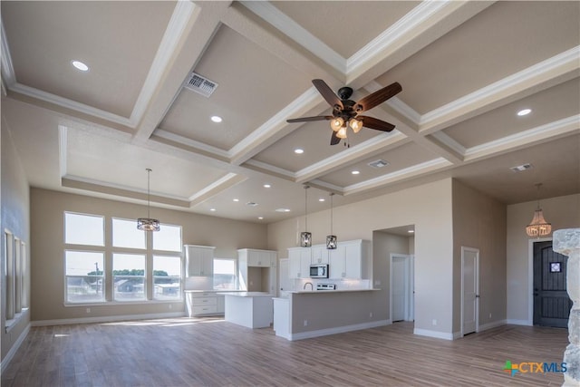 unfurnished living room with light wood-type flooring, visible vents, coffered ceiling, baseboards, and a towering ceiling