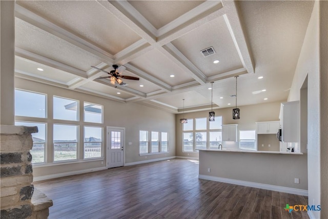 unfurnished living room featuring plenty of natural light, coffered ceiling, and dark wood-style flooring