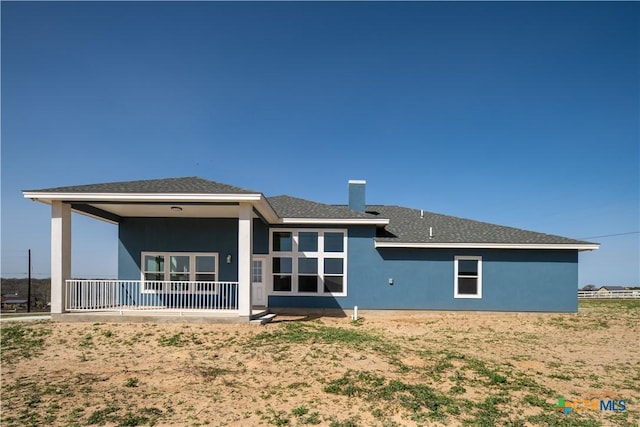 rear view of house featuring roof with shingles and stucco siding