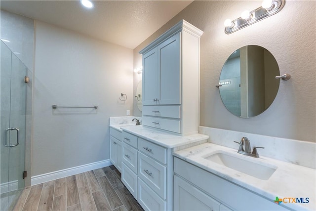 bathroom featuring vanity, a shower stall, baseboards, and wood tiled floor